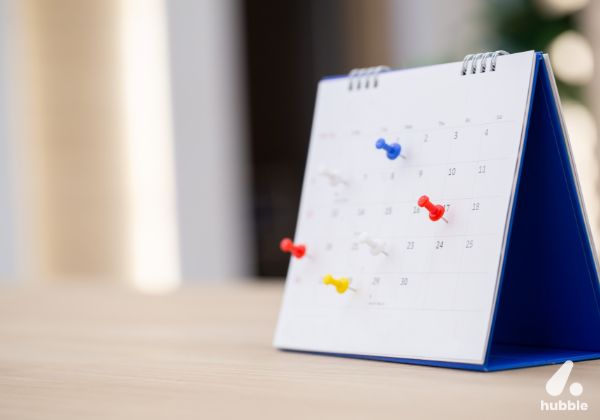 Desk calendar with coloured push pins marking key dates, representing planning impactful corporate events.