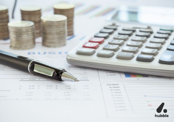 Calculator, pen, and stacked coins on financial documents, representing monetary vs. non-monetary rewards.