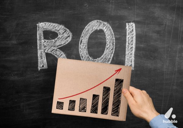 Hand holding a chart with an upward trend in front of "ROI" on a chalkboard, symbolizing event ROI measurement
