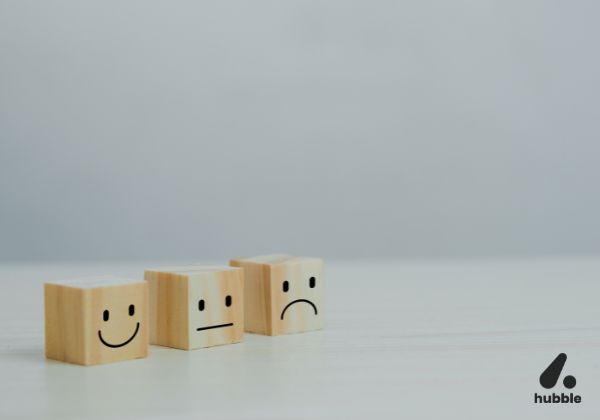 Wooden blocks with smiley, neutral, and sad faces representing customer feedback collection methods.