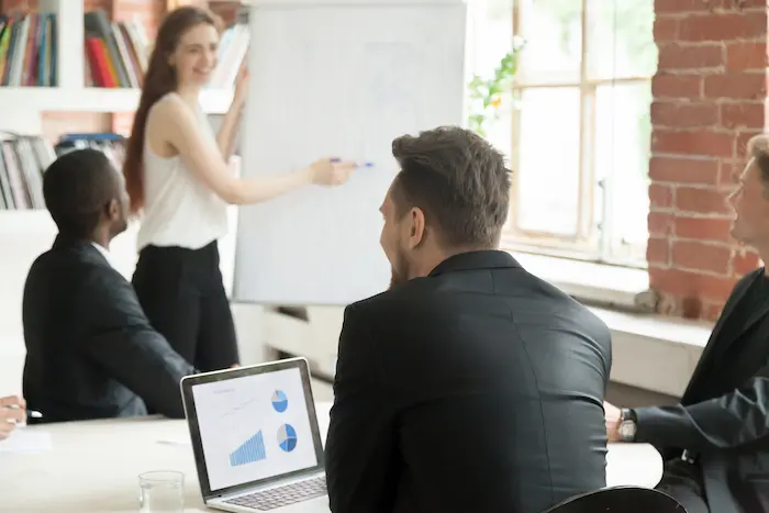 Formation pour devenir coach immobilier : une formatrice présente des graphiques à des professionnels attentifs lors d’un atelier interactif en salle.