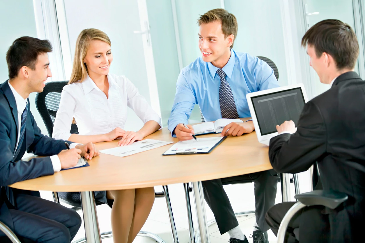 Quatre personnes consultant des dossiers autour d'une table.