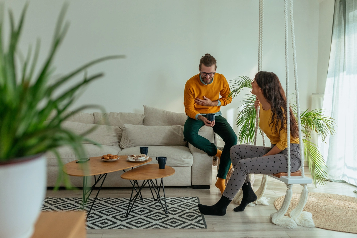 Un homme et une femme en pleine discussion dans un salon avec des plantes.