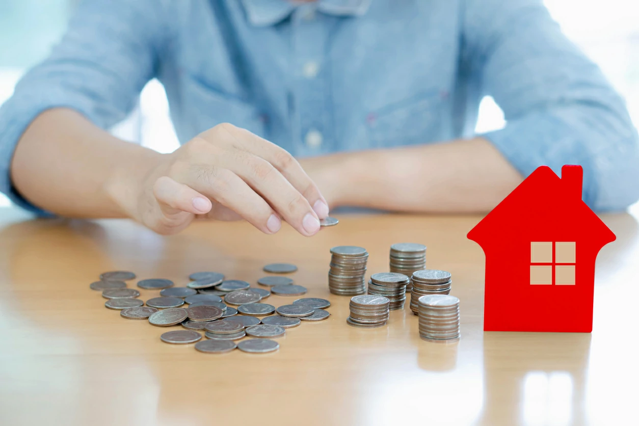Homme comptant des pièces de monnaie à côté d'une carte en forme de maison.