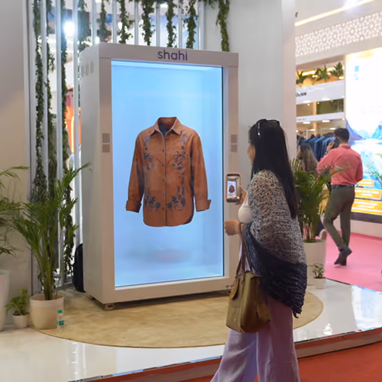 Visitors stopping to watch Shahi holographic fashion display at an exhibition