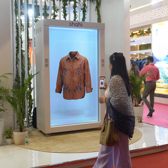 Visitors stopping to watch Shahi holographic fashion display at an exhibition