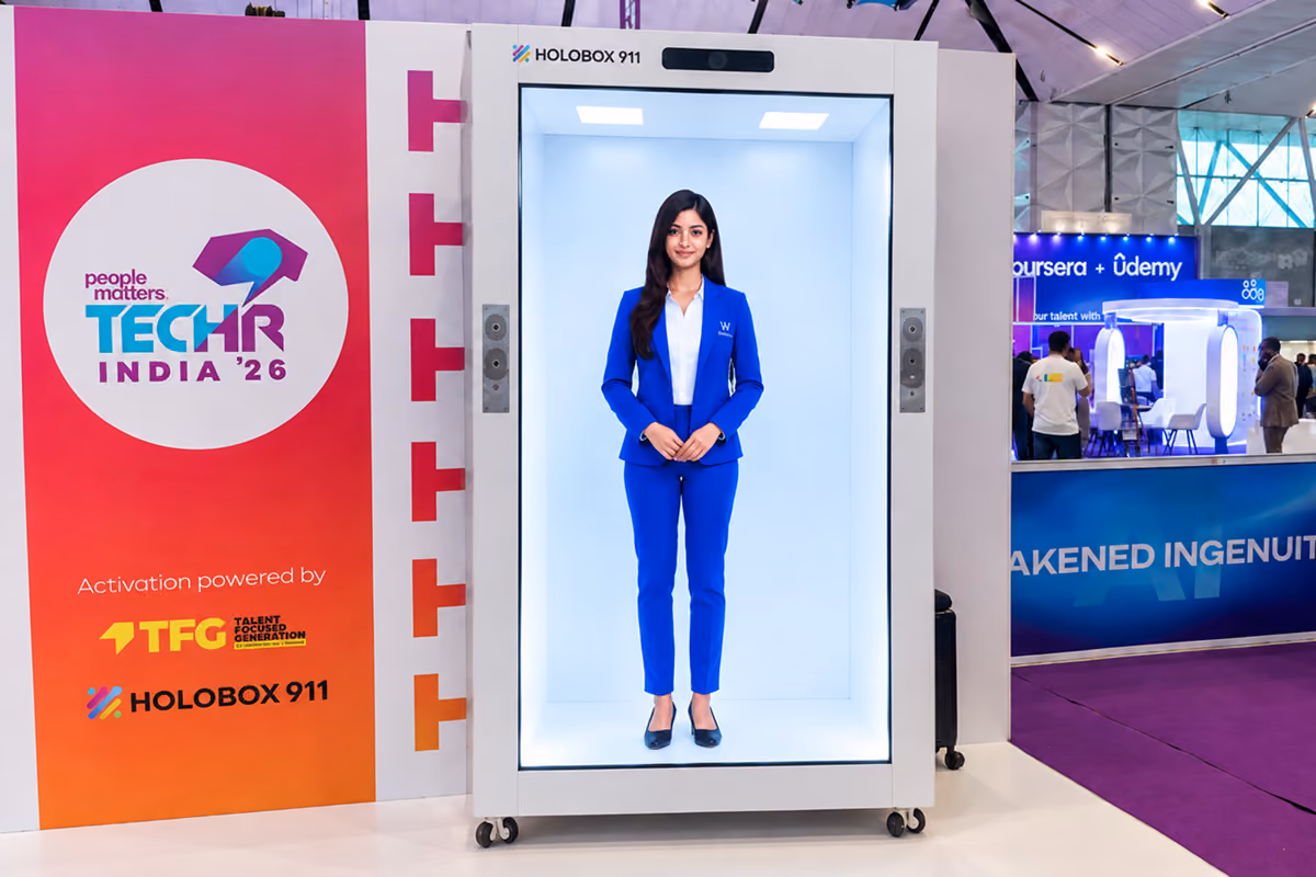 A life-size AI avatar hosting visitors on a HoloBox911 display at the People Matters TechHR conference