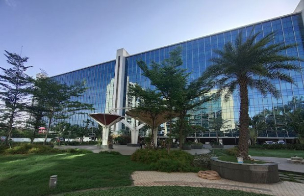 Exterior view of a glass-fronted office building with a landscaped forecourt.