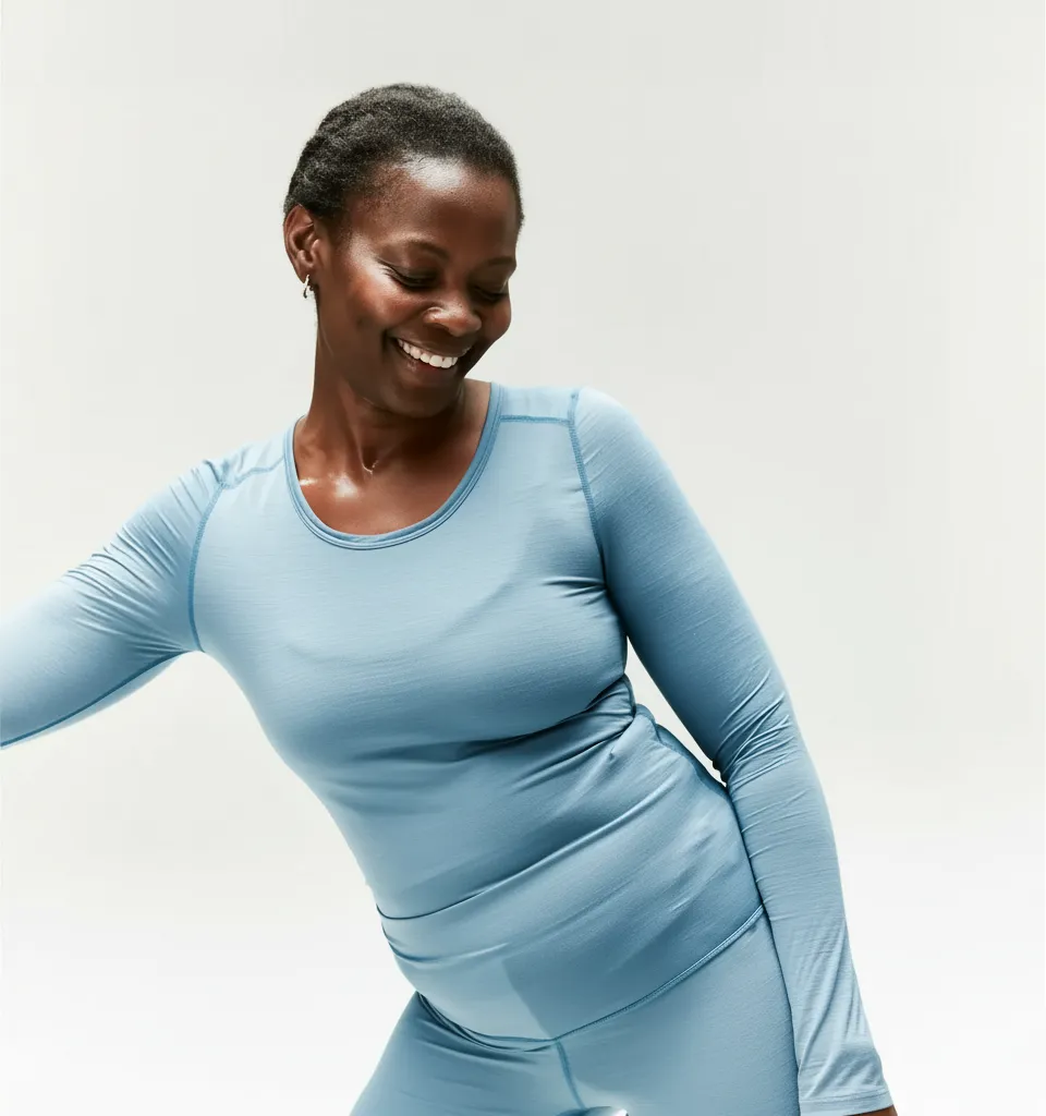 Smiling woman in light blue athletic wear against a plain white background.