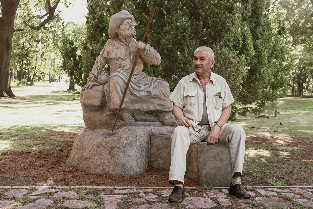 Hombre sentado en el banco de la escultura de Santiago