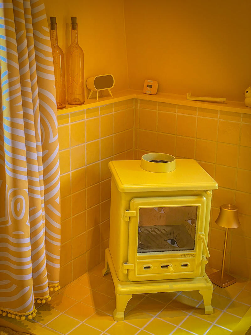 An all yellow colour scheme idea for a boat bedroom, a yellow log burner sits a in a tiled corner.