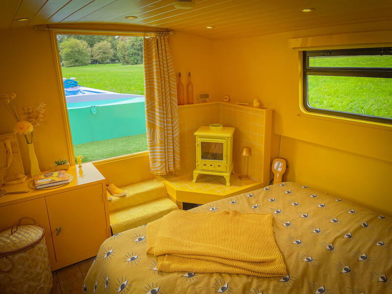 An all yellow colour scheme idea for a small and cosy narrow boat bedroom with a log burner