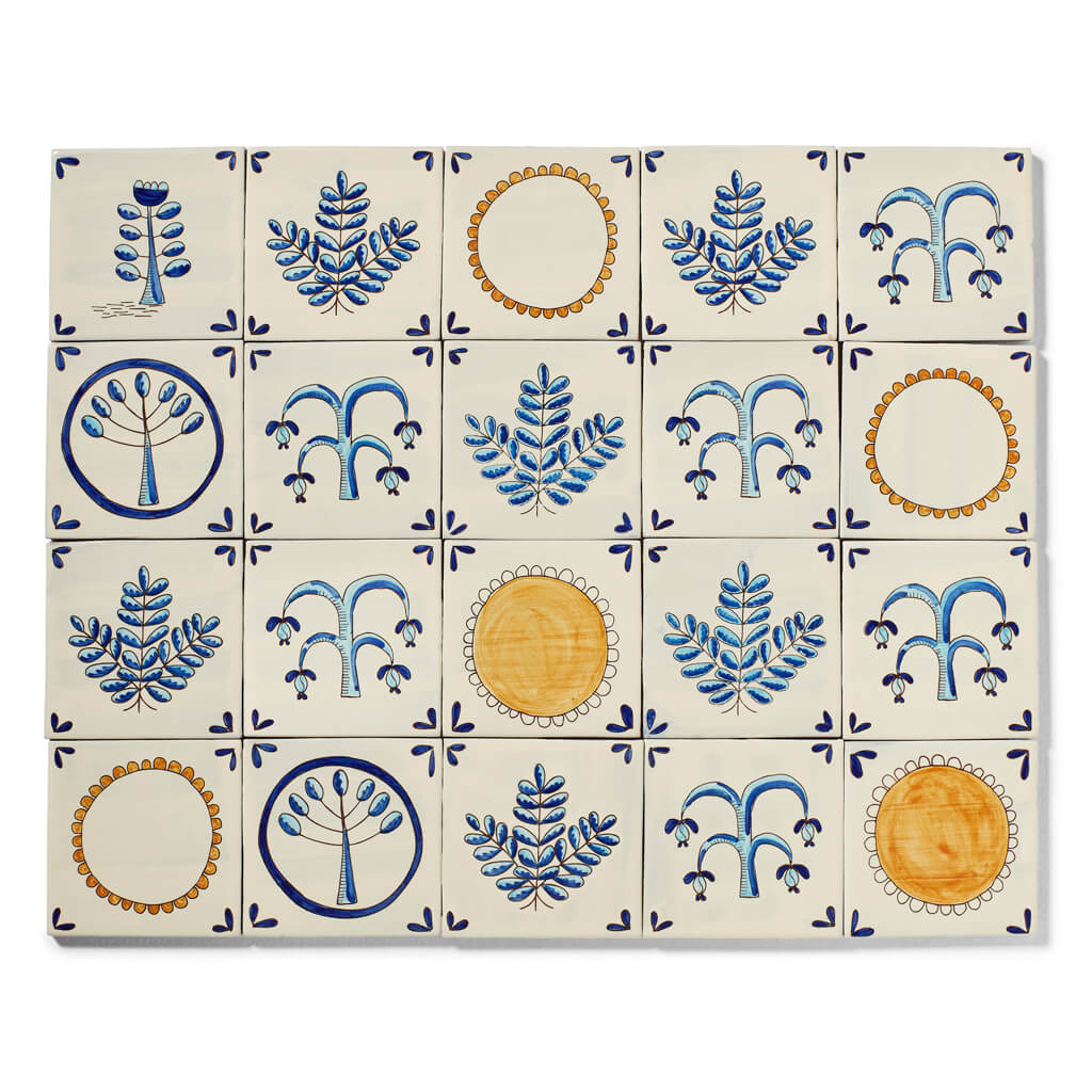 Grid of sixteen cream tiles each with blue stylized trees and leaf designs in four repeating patterns.