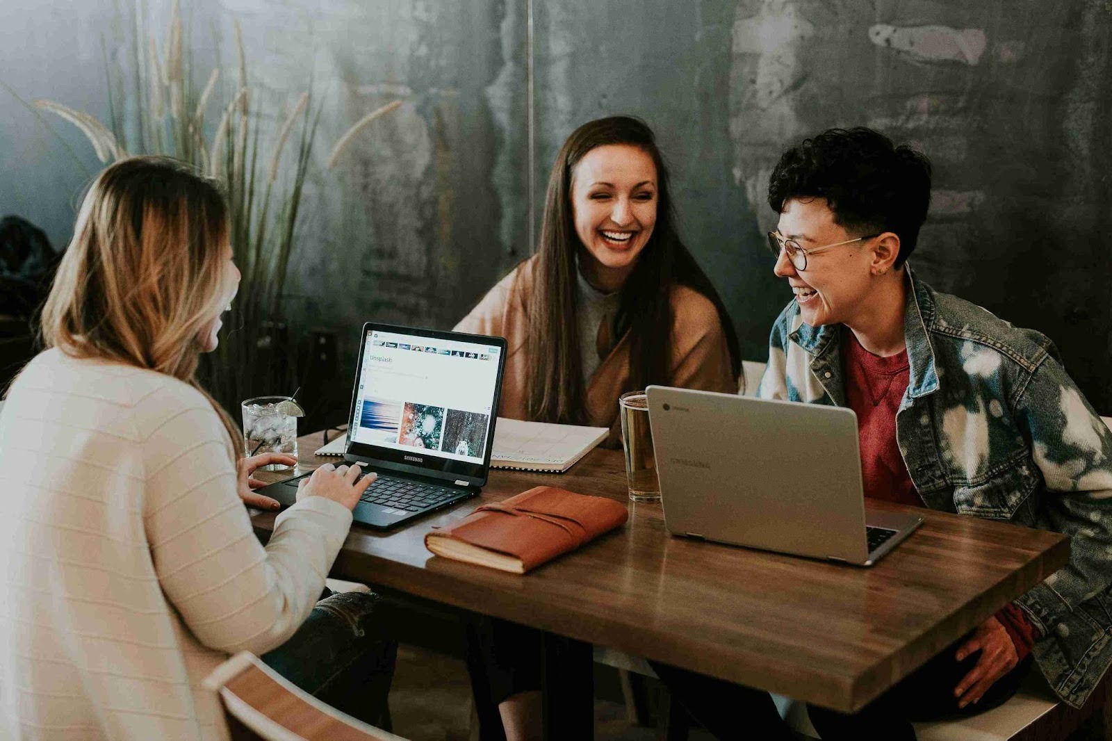 Three people are sitting at a table and laughing.