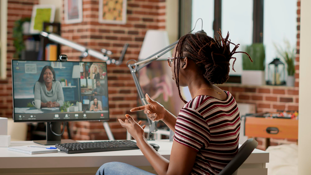 Hybrides Arbeiten im Homeoffice: Eine Frau sitzt am Schreibtisch und hält eine virtuelle Konferenz.
