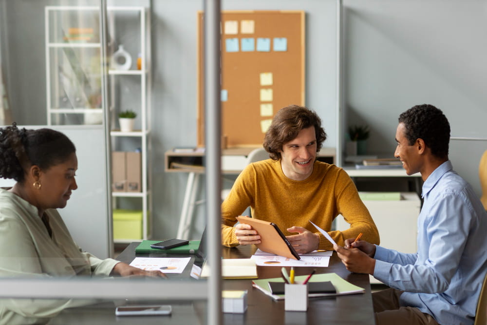 Three employees are talking in a workplace-sharing office.