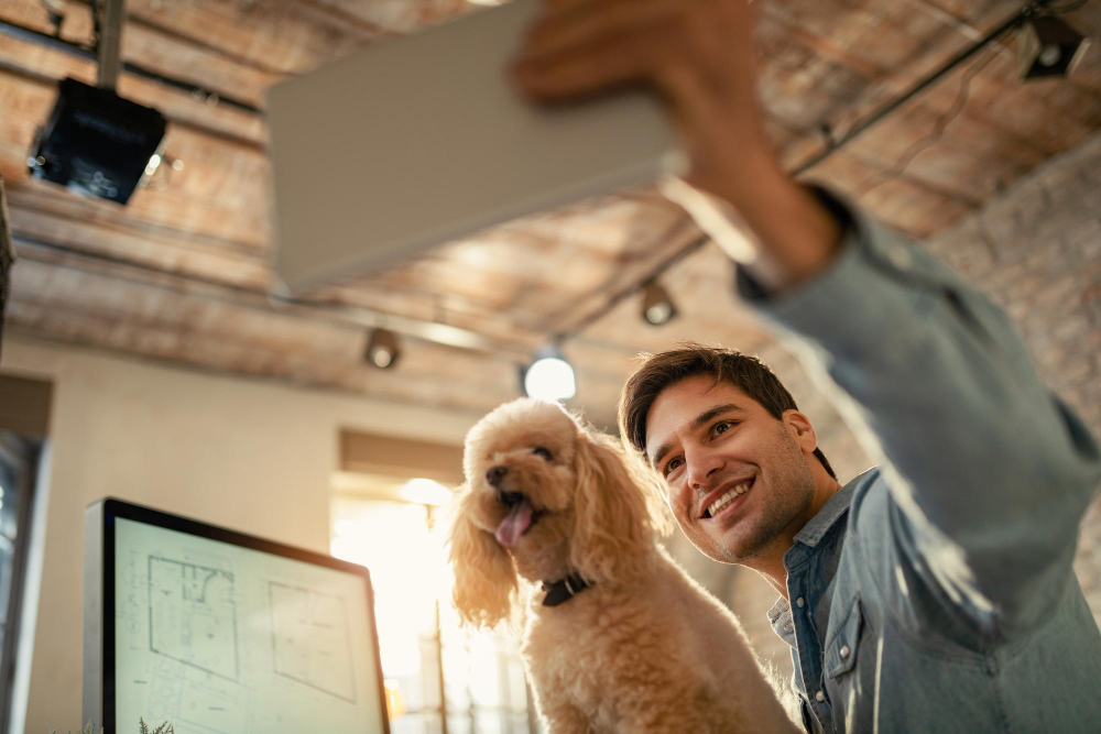 Een man op kantoor maakt een selfie met een hond op schoot.