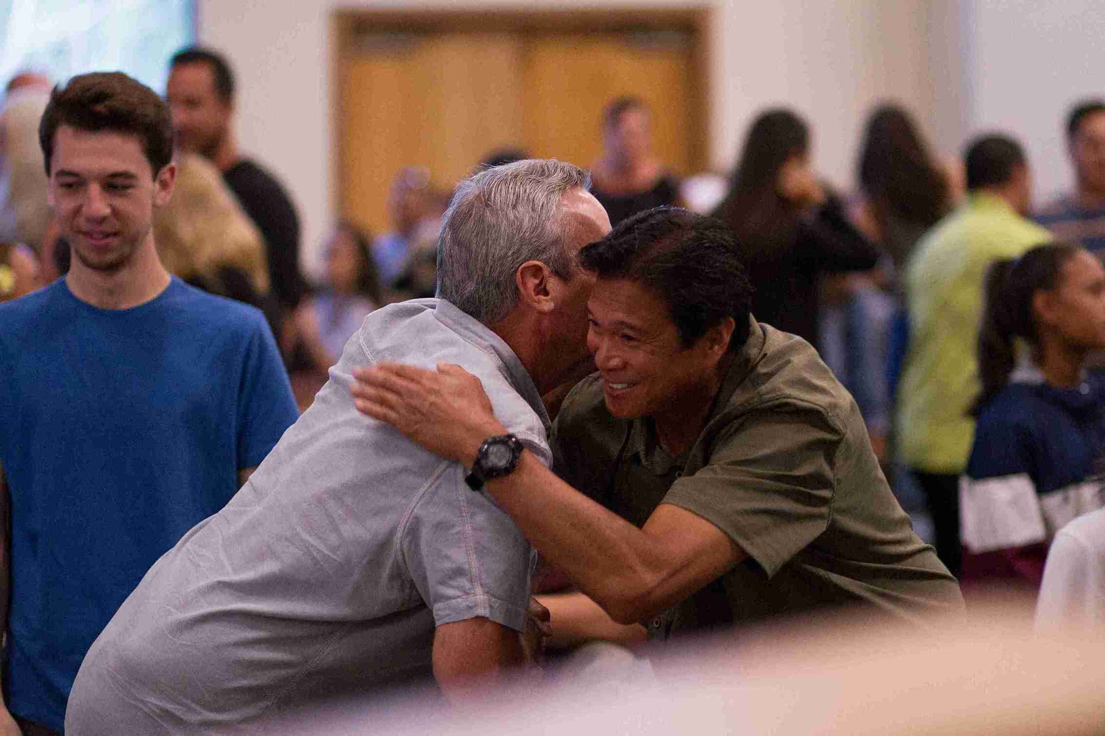 Two members of a congregation embrace during a large congregational meeting.