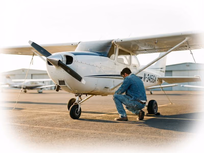 Pilot doing preflight walkaround on a Cessna 172 at a general aviation airport