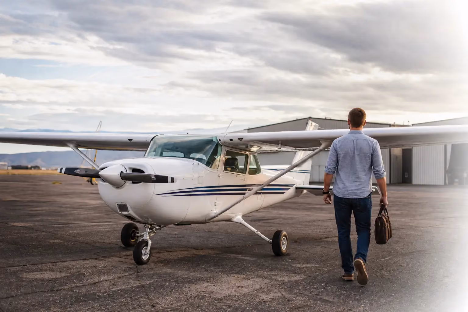 Pilot in casual clothing approaching a Cessna aircraft on a general aviation ramp for a business trip