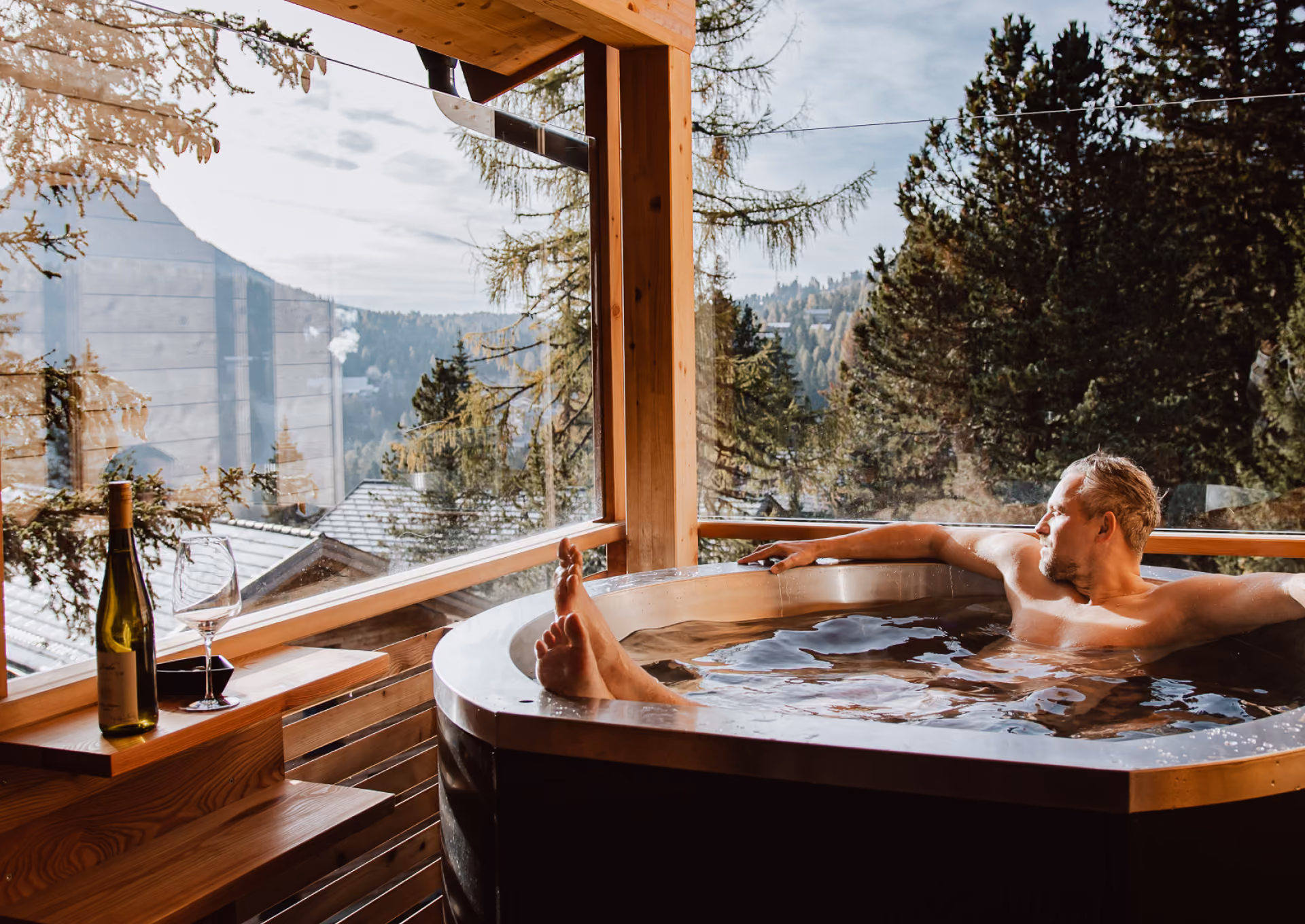 Privater Spa-Bereich im Naturchalet Turracher Höhe: Gast entspannt im Holzbottich mit Panoramablick in den Bergwald – betrieben von ALPS RESORTS