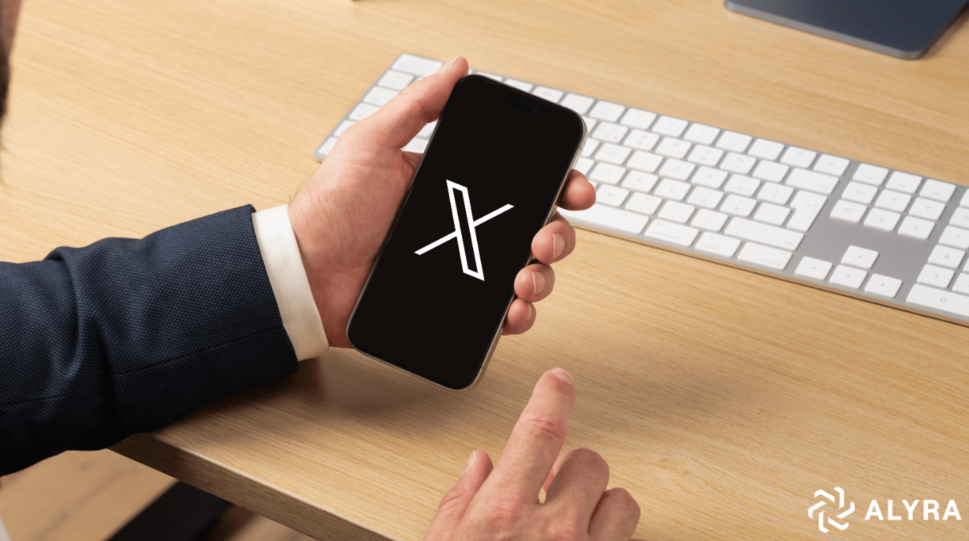 Homme tenant un téléphone avec le logo X s'affichant