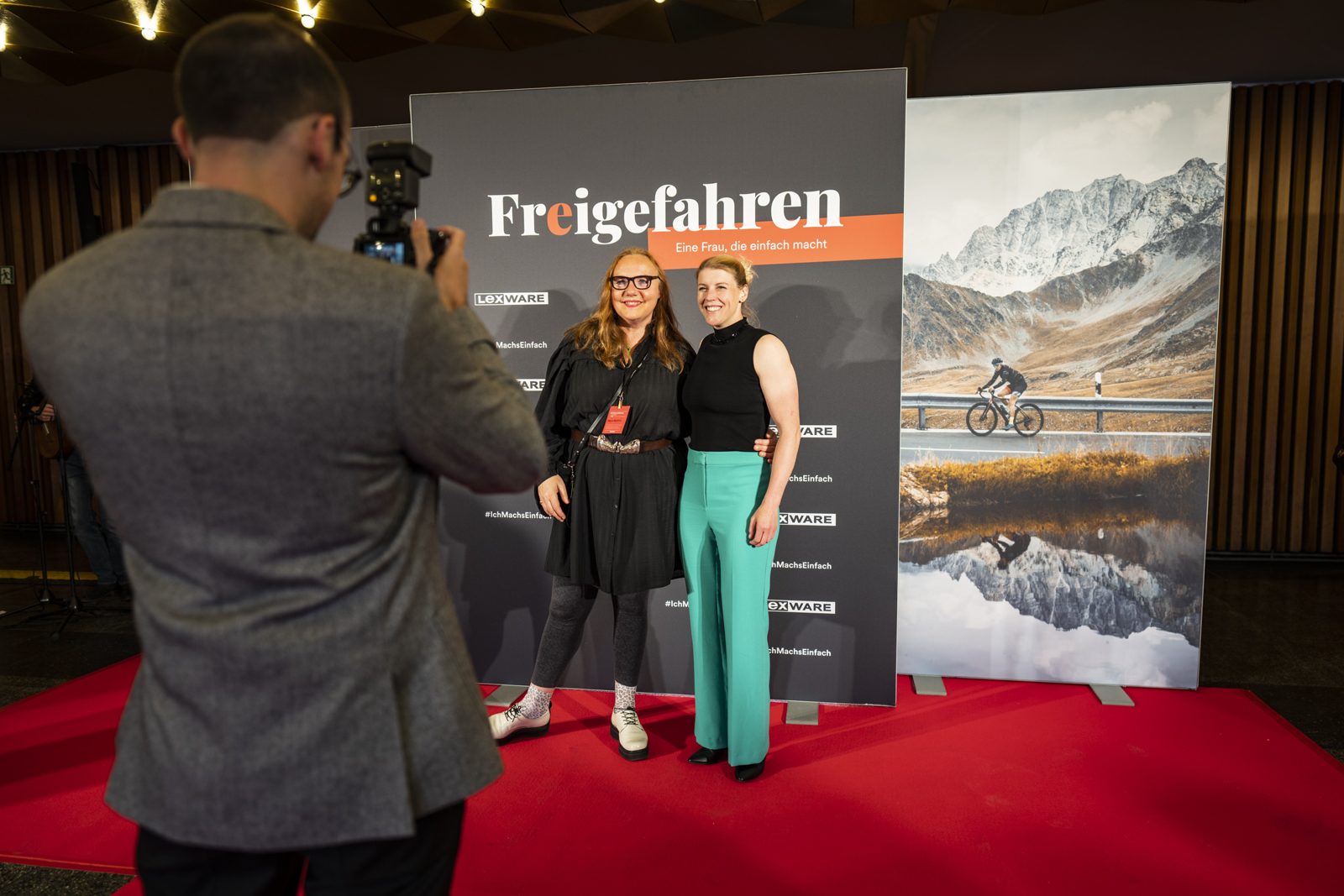 Zwei Gäste posieren vor der Fotowand mit dem Filmplakat