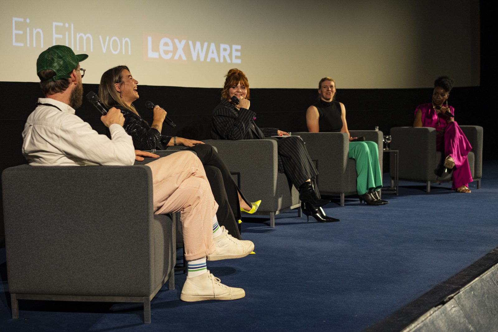 Fünf Personen im Talk auf der Bühne vor der Kinoleinwand