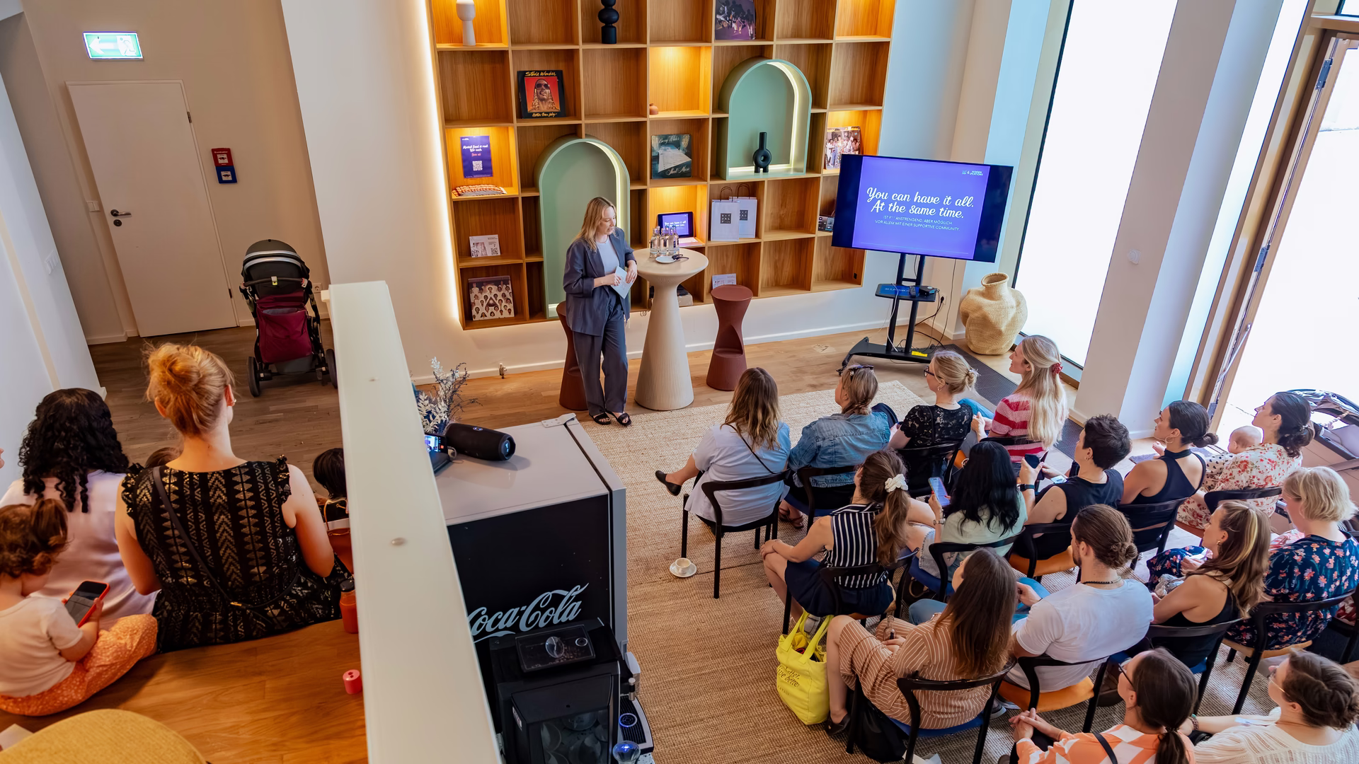 Sprecherin an einem Stehpult vor einer Leinwand mit dem Schriftzug You can have it all, davor sitzendes Publikum beim It's a Parents Thing Brunch.