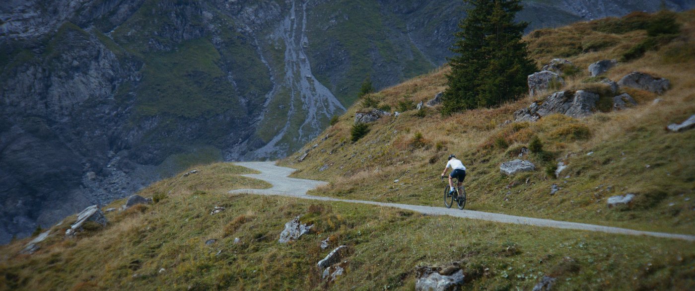 Einzelne radfahrende Person auf einem schmalen Weg an einem Berghang