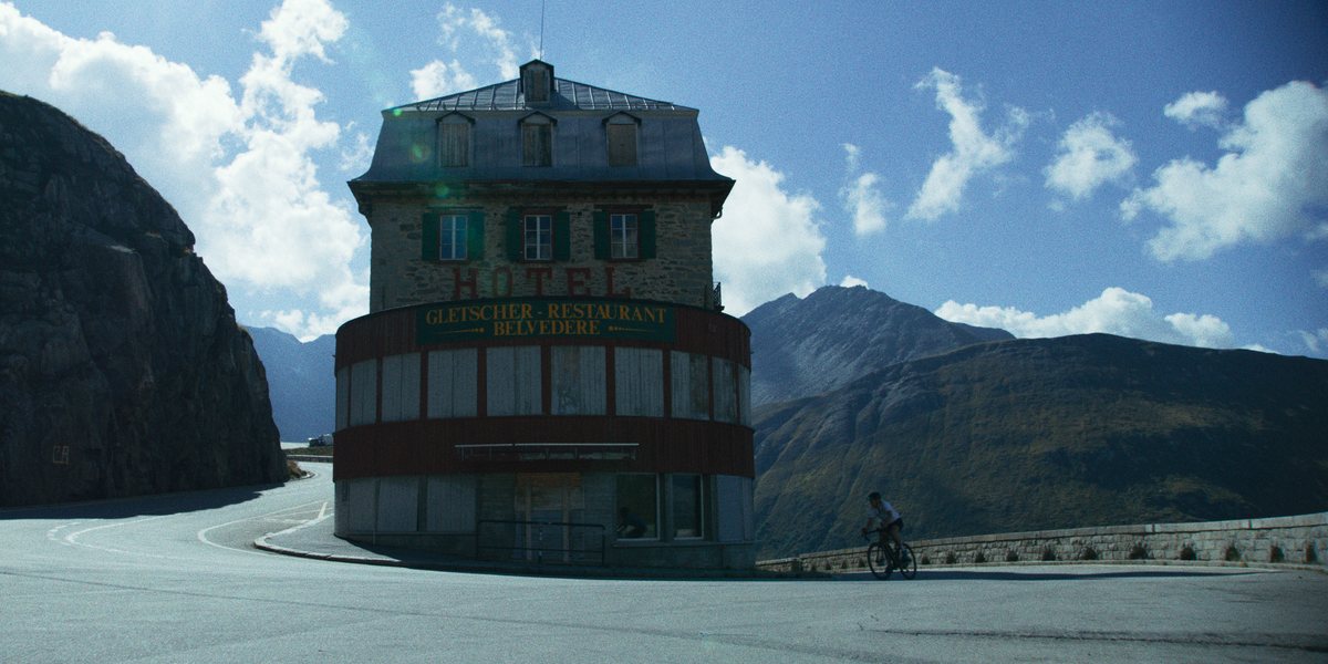 Radfahrende Person passiert das Hotel Belvedere mit Gletscher-Restaurant an einer Passstraße