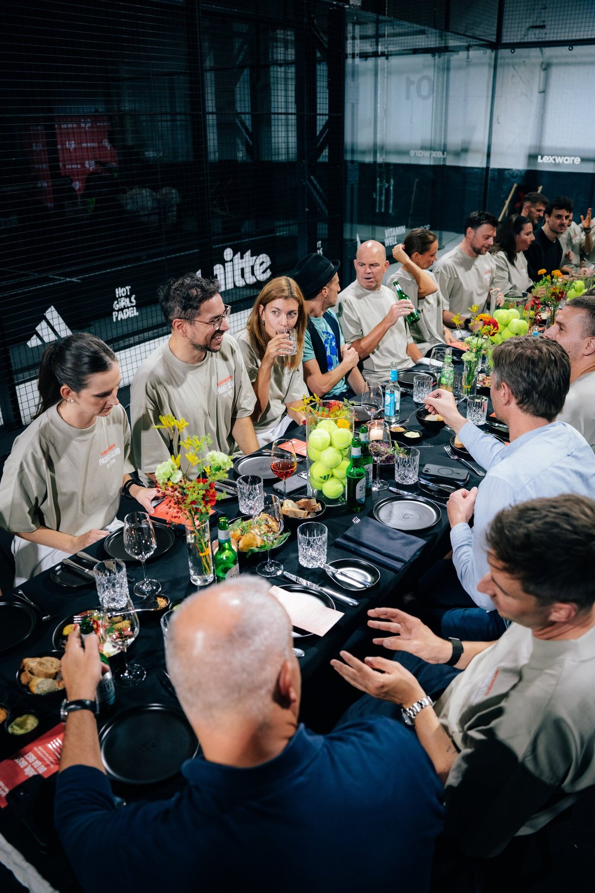 Blick von oben auf die lange Tafel auf dem Padel-Court, Gäste beim gemeinsamen Dinner.