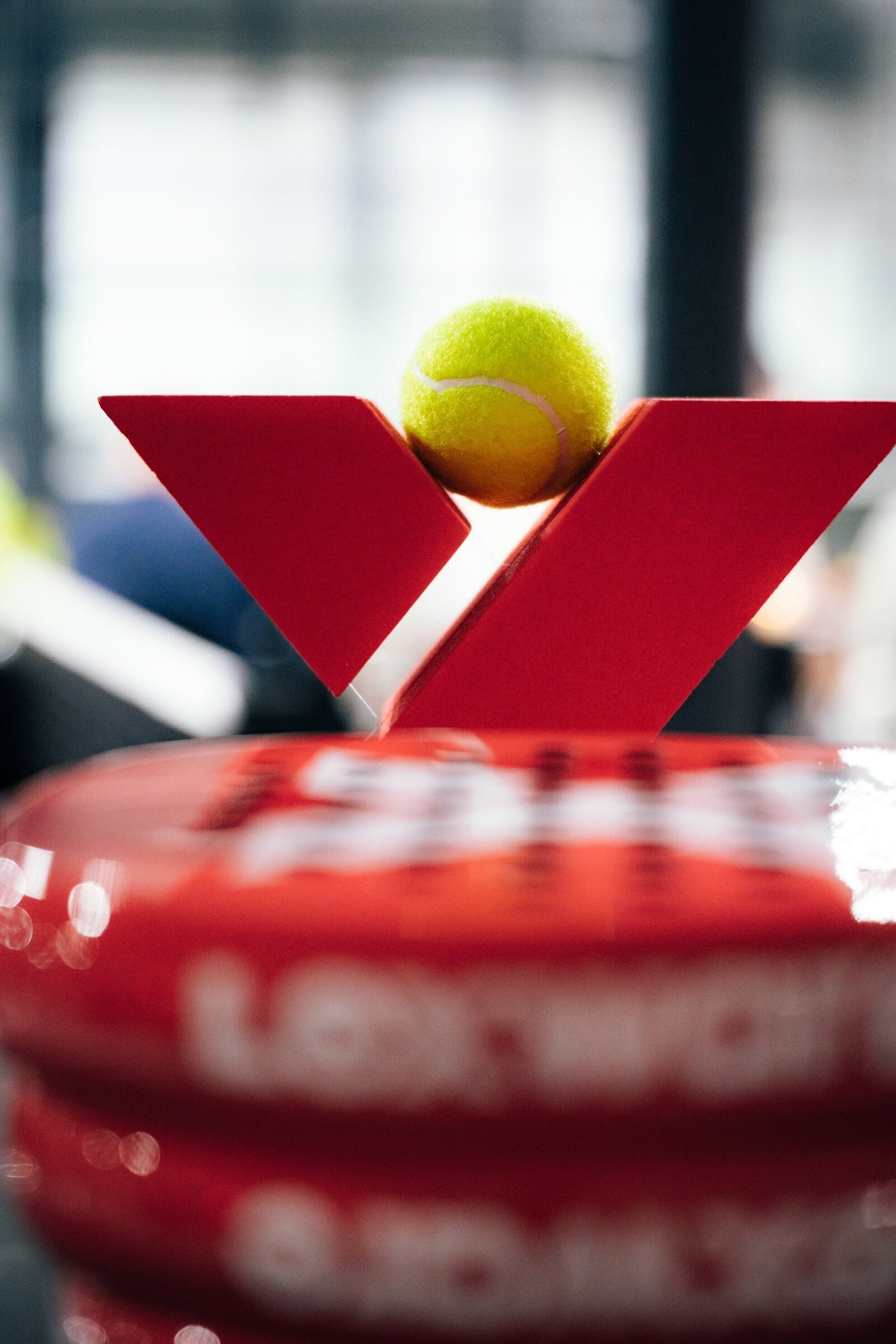 Rotes Padel-X-Logo mit gelbem Tennisball.