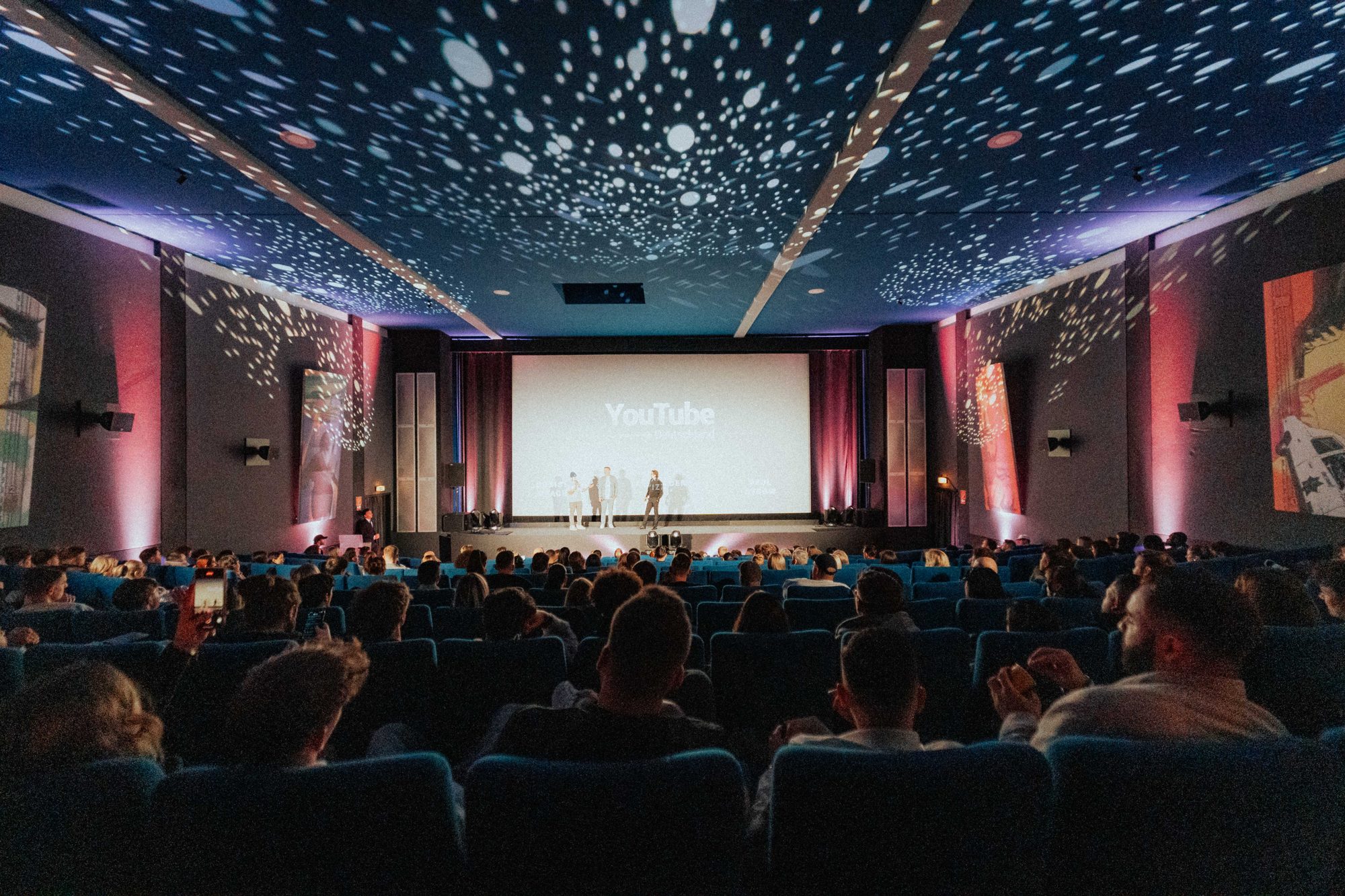 Voller Kinosaal mit Sternenhimmel an der Decke, vorn auf der Bühne die Premiere von YouTube Deutschland