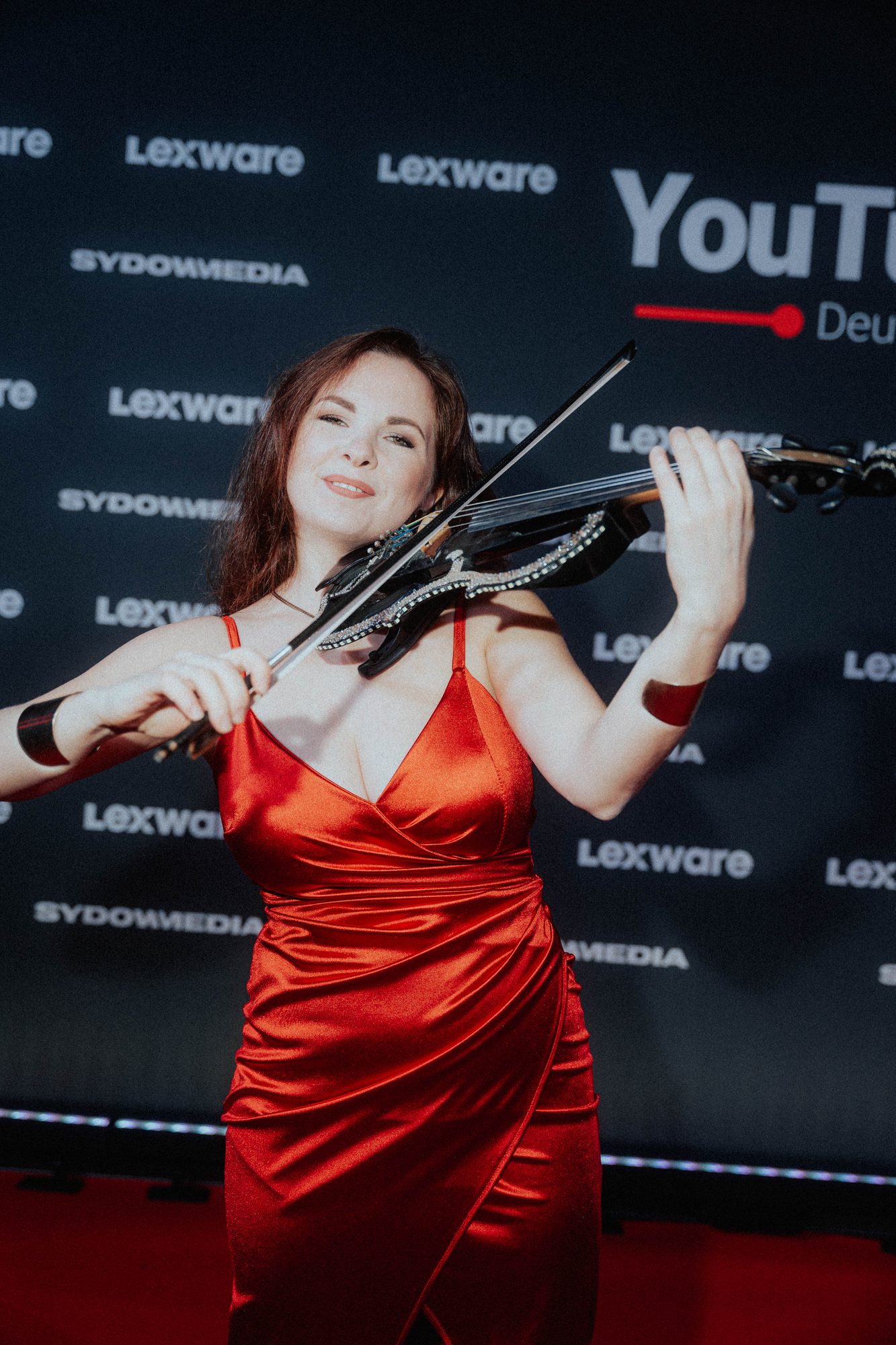 Opening Act spielt E-Geige vor der Premierenwand von YouTube Deutschland