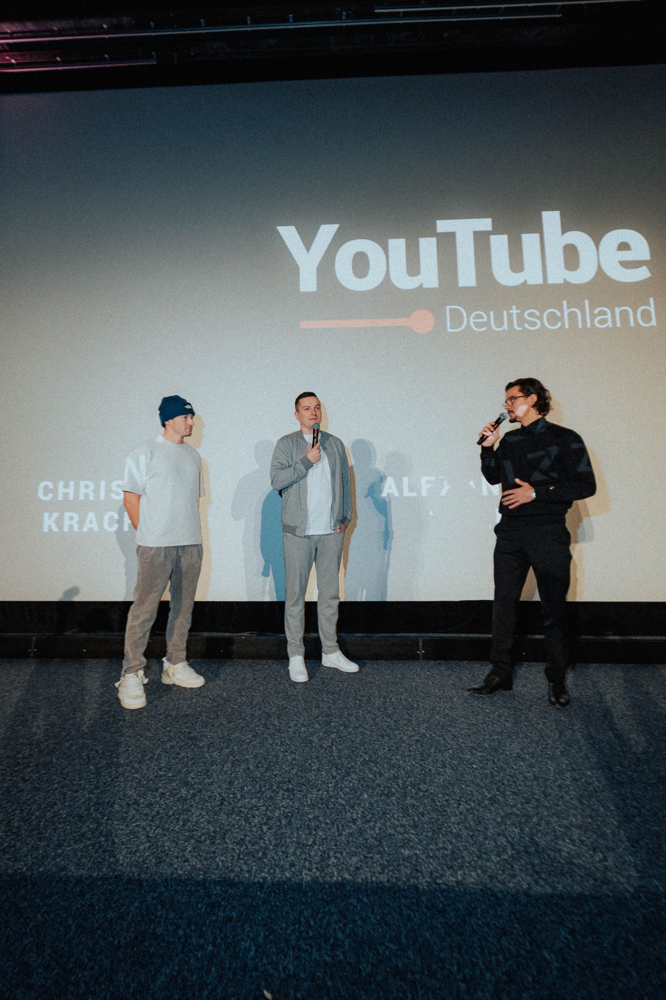 Drei Protagonisten der Dokureihe auf der Bühne vor dem Logo von YouTube Deutschland