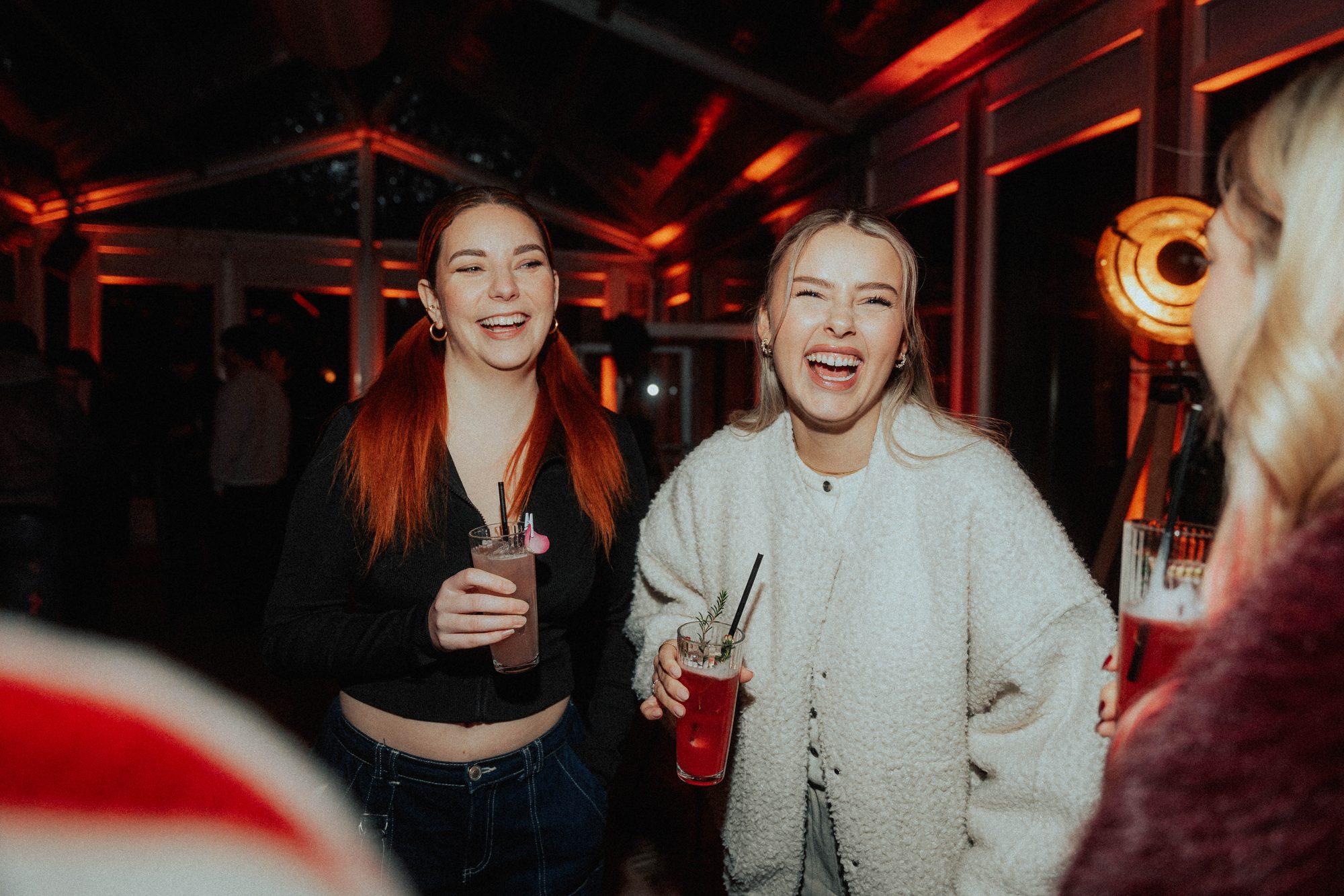 Zwei Gäste lachen laut mit Cocktail in der Hand