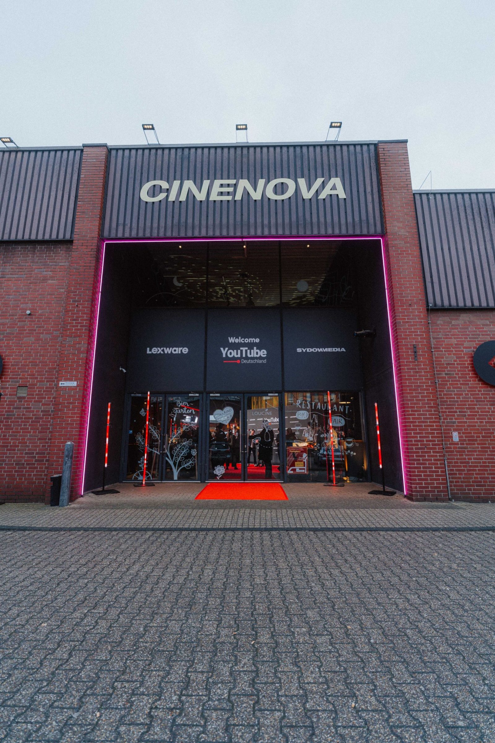 Das Cinenova in Köln am Abend mit leuchtendem Eingang und rotem Teppich