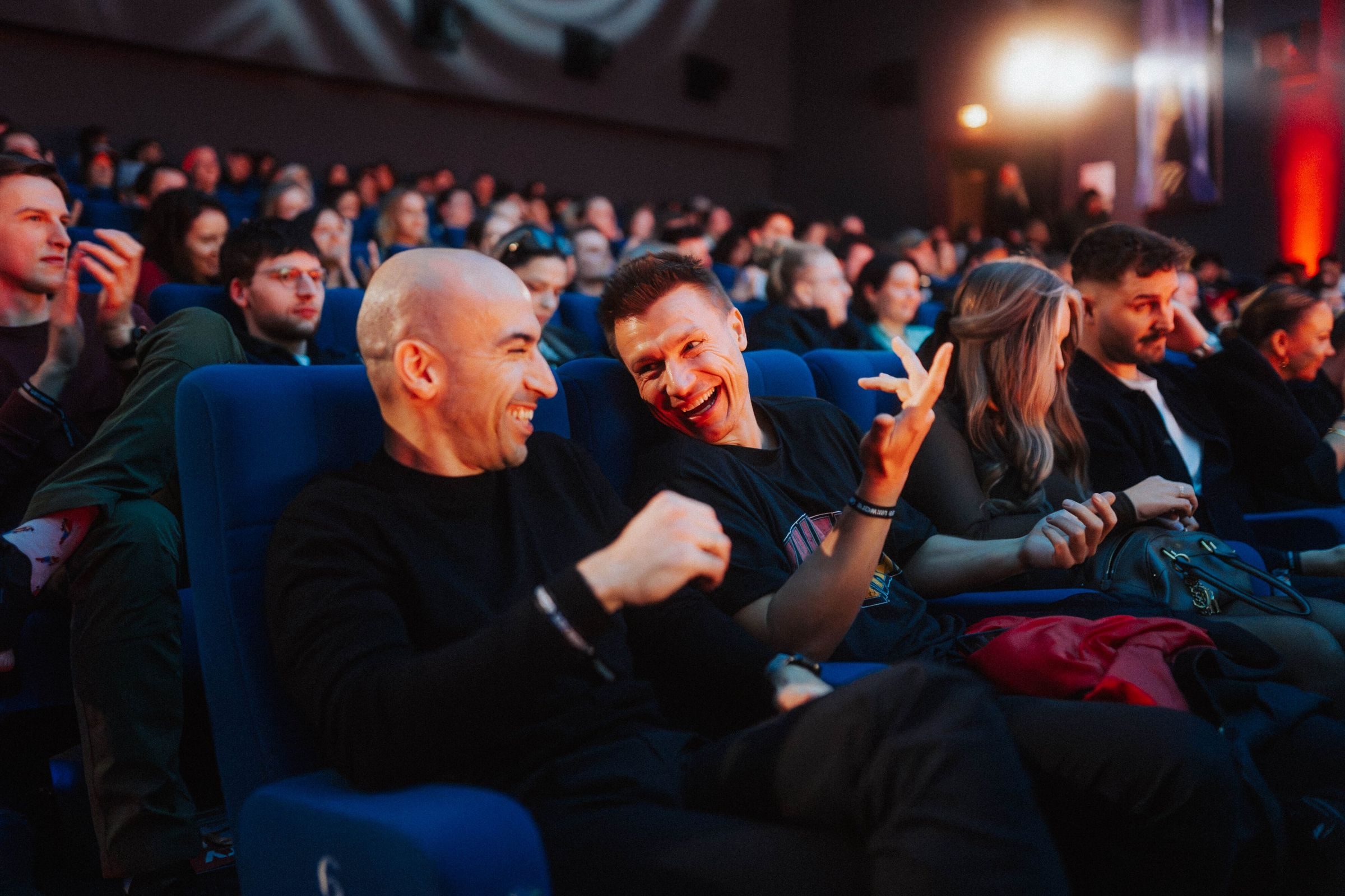 Zwei Männer lachen im Publikum und klatschen sich ab