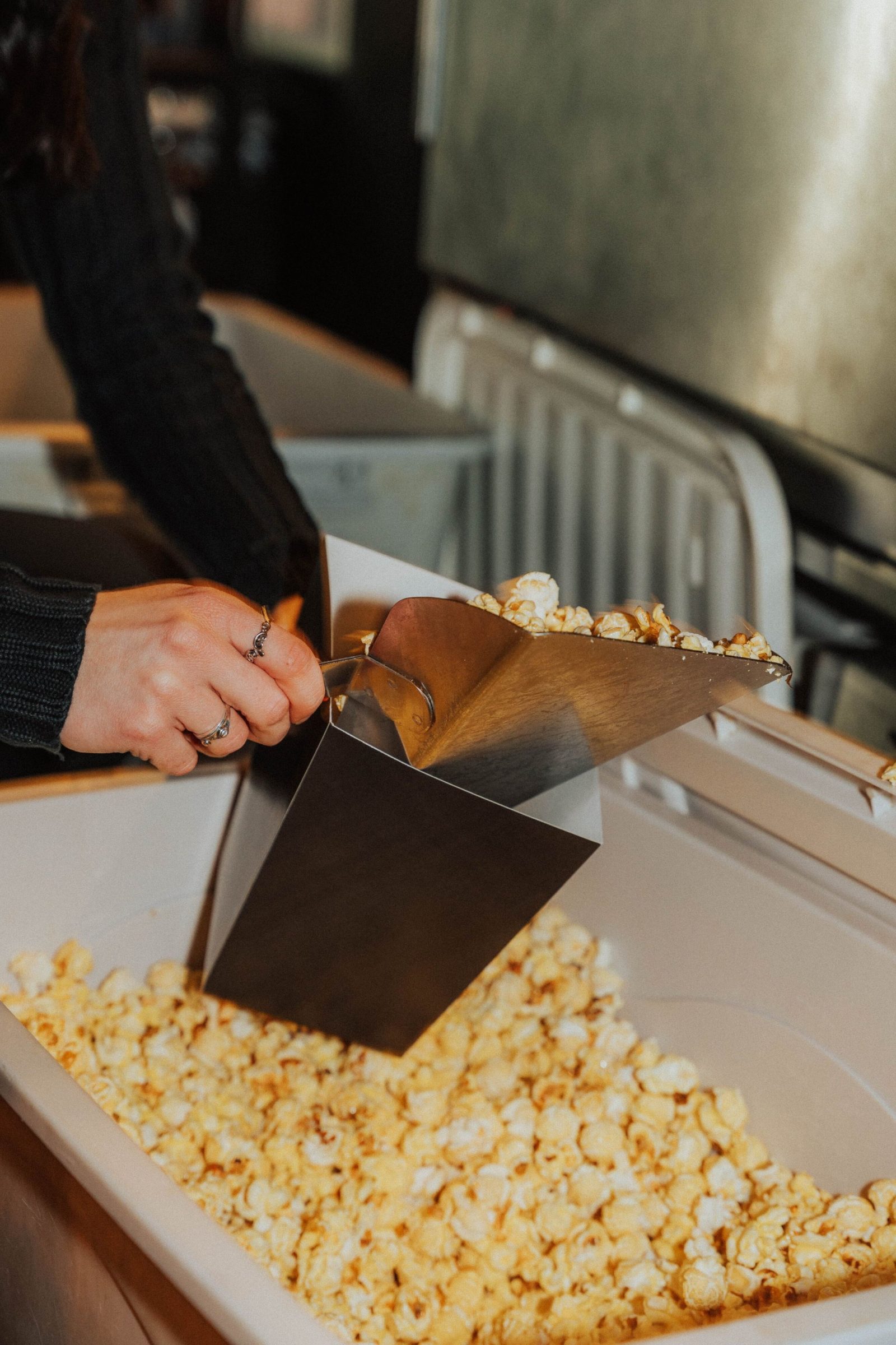 Frisches Popcorn wird am Popcorn-Stand in eine Tüte geschaufelt