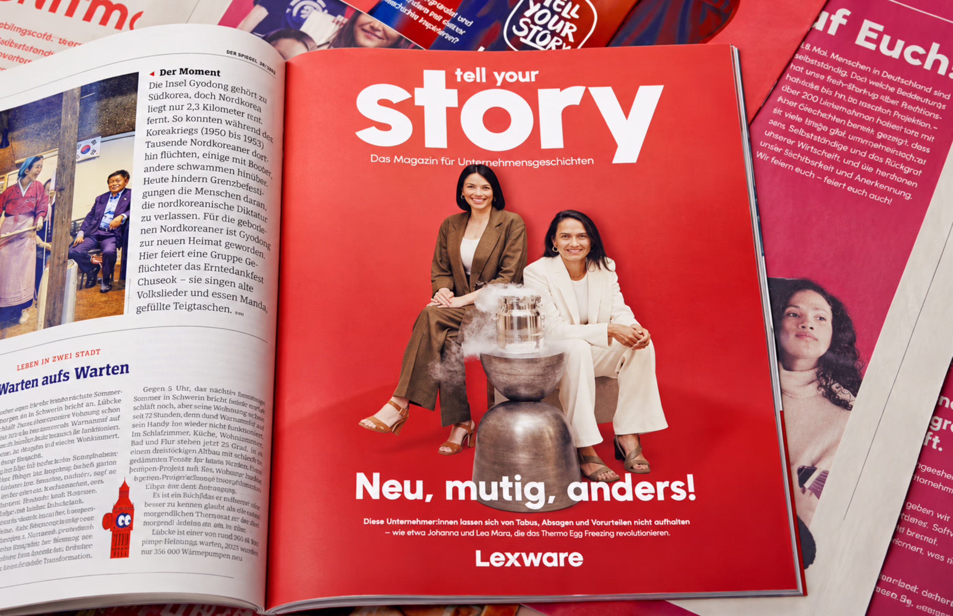 Mehrere Magazine auf einem Tisch, in der Mitte das rote Cover von „tell your story“ mit zwei lächelnden Gründerinnen und der Schlagzeile „Neu, mutig, anders!“