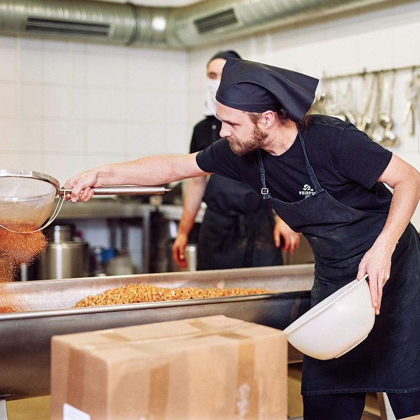 Ein Gründer von fairfood Freiburg beim Würzen von Nüssen - Beitragsbild von Lexware Tell Your Story