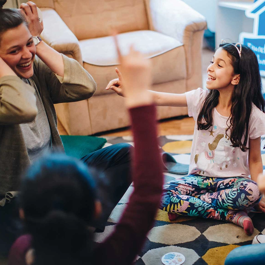 Eine Frau und drei Kinder sitzen auf den Boden und spielen zusammen - Beitragsbild von Lexware Tell Your Story