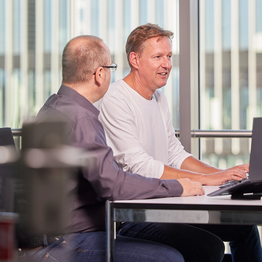 Die beiden Hersteller der App Meet your Doc am Schreibtisch vor zwei Bildschirmen - Beitragsbild von Lexware Tell Your Story