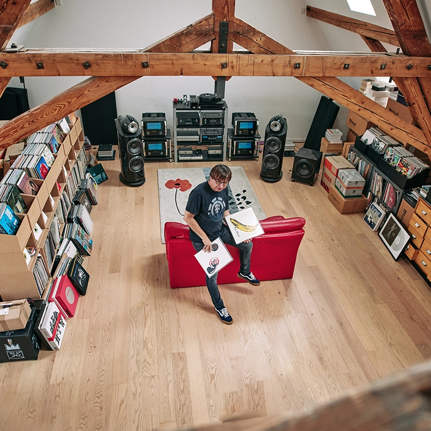 Raimund Flöck auf roten Sofa mit Plattencover von Velvet Underground in der Hand - Beitragsbild von Lexware Tell Your Story
