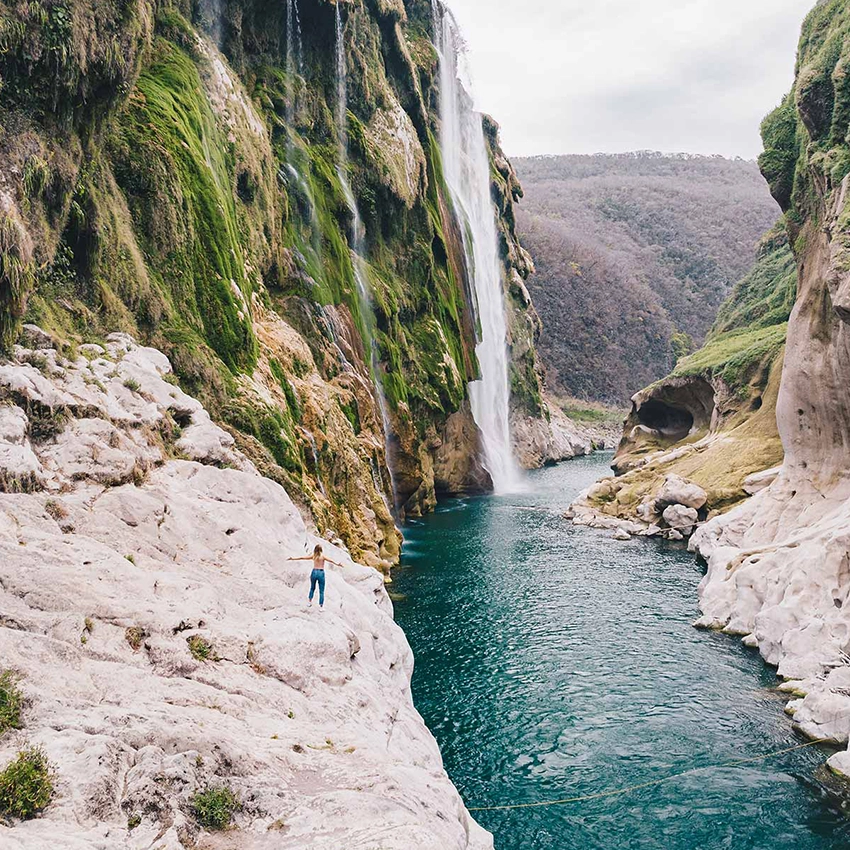 Frau mit ausgebreiteten Armen vor Fluss und Wasserfall in einem Canyan - Beitragsbild von Lexware Tell Your Story