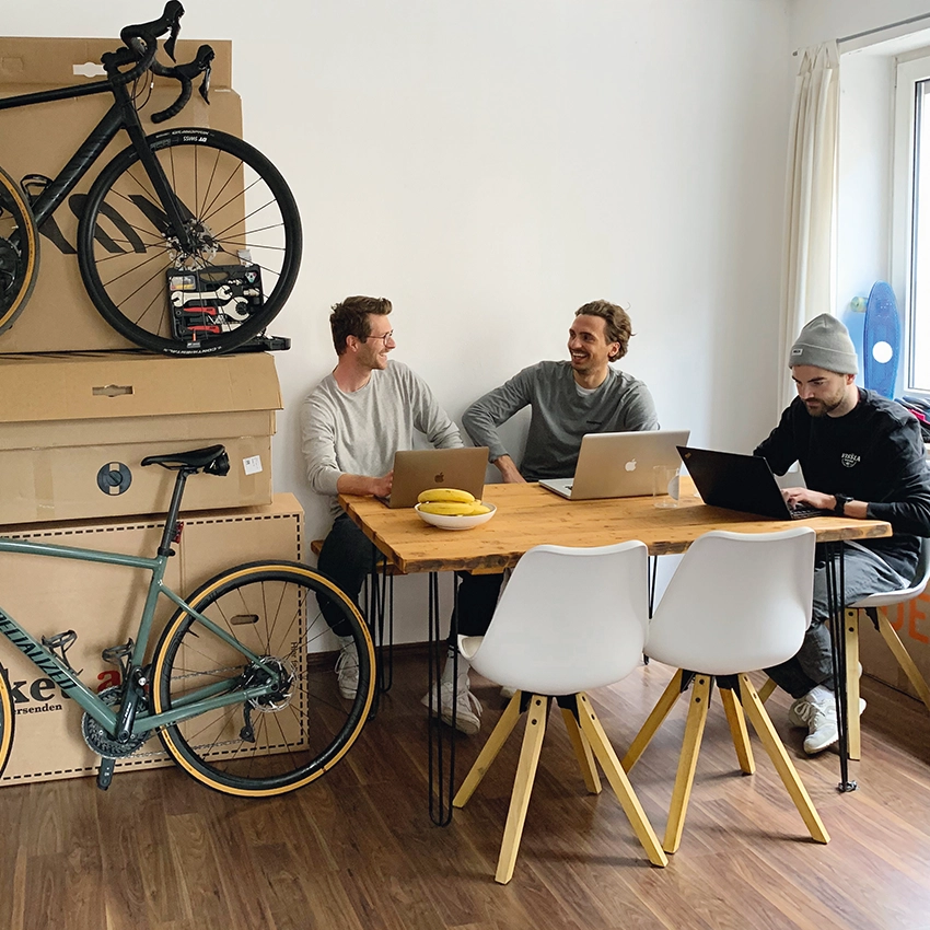 Die Drei Gründer des Online-Marktplatzes Buycycle an Holztisch vor Laptops - Beitragsbild von Lexware Tell Your Story