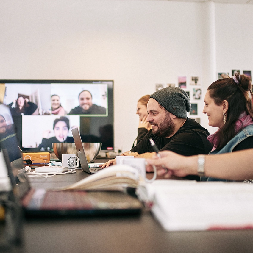 Zwei Frauen und ein Mann an Schreibtisch vor Laptop - Beitragsbild von Lexware Tell Your Story