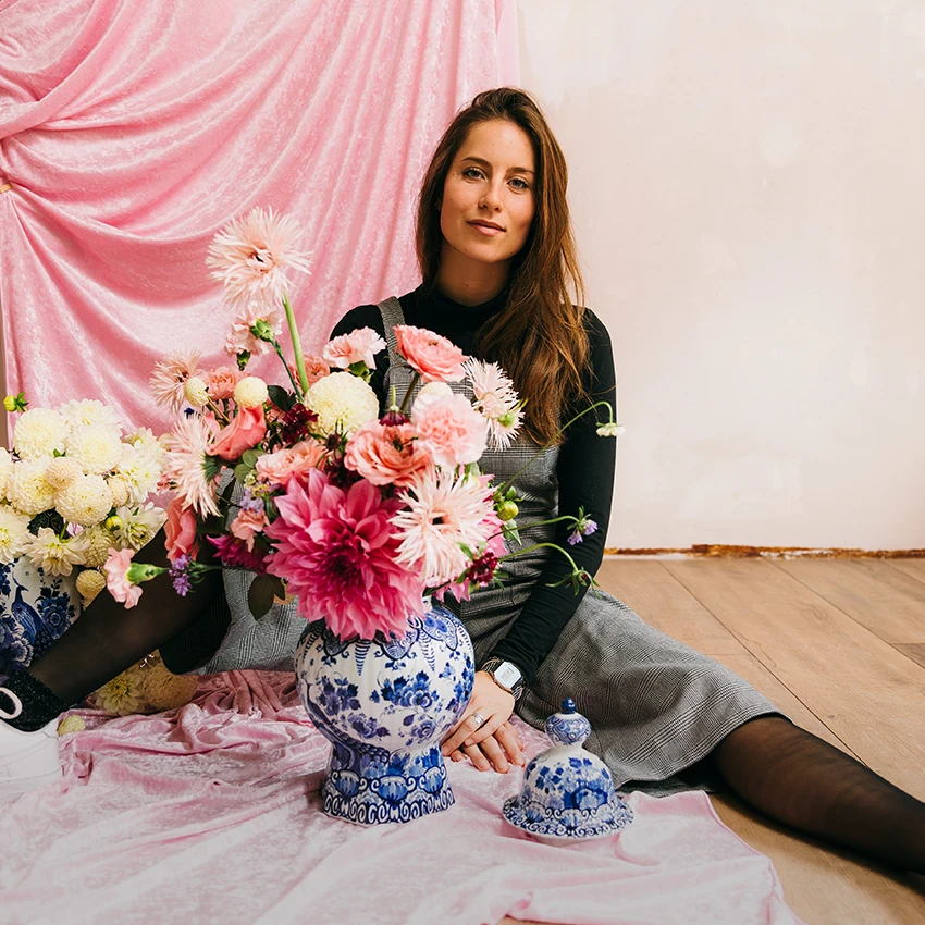 Valentina sitzt auf dem Boden hinter einem Blumenstrauß.