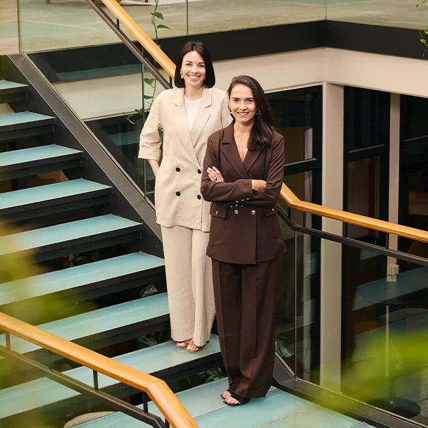 Das Gründerduo Johanna Rief und Lisa Maria Ladner von Fyrce Care stehen auf einer Treppe